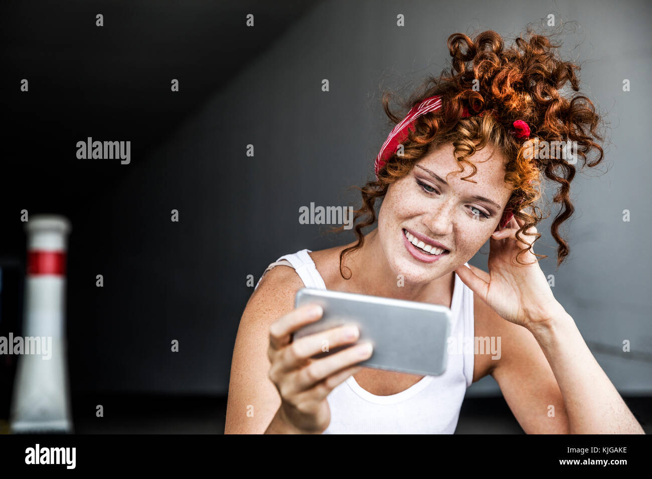Redheaded sorridente donna azienda telefono cellulare Foto Stock