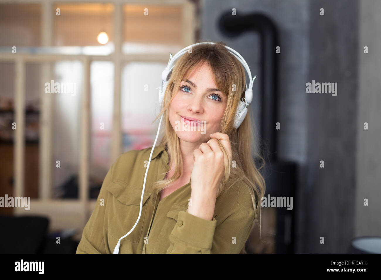 Sorridente donna bionda ascolto di musica con cuffie Foto Stock
