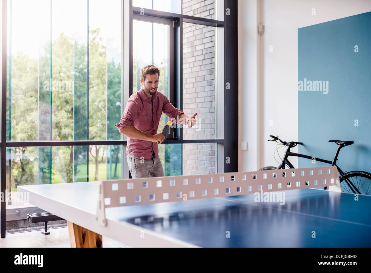 Uomo in sala pausa di ufficio moderno giocando a ping-pong Foto Stock