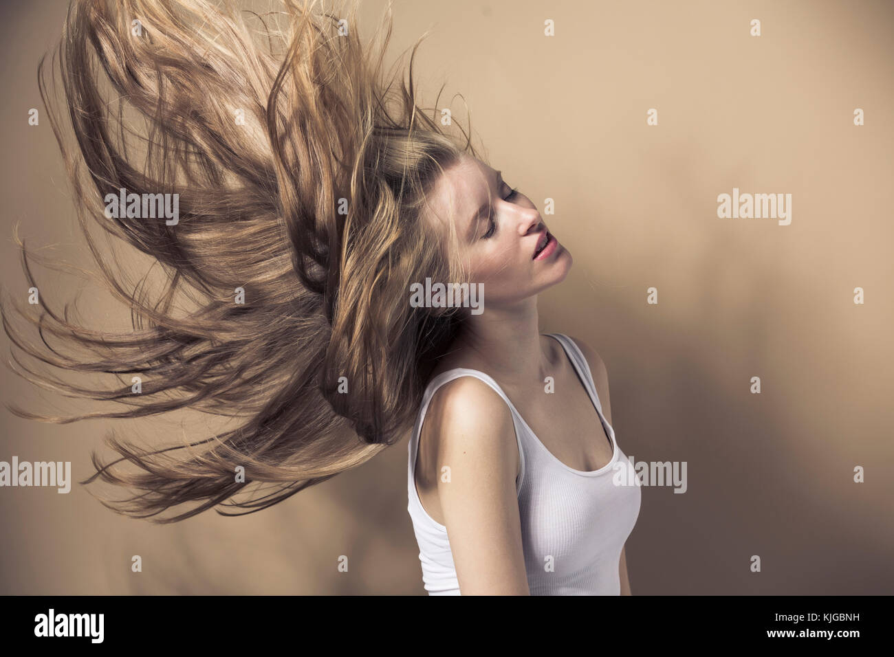 Ritratto di giovane donna bionda nel lanciare i suoi capelli Foto Stock
