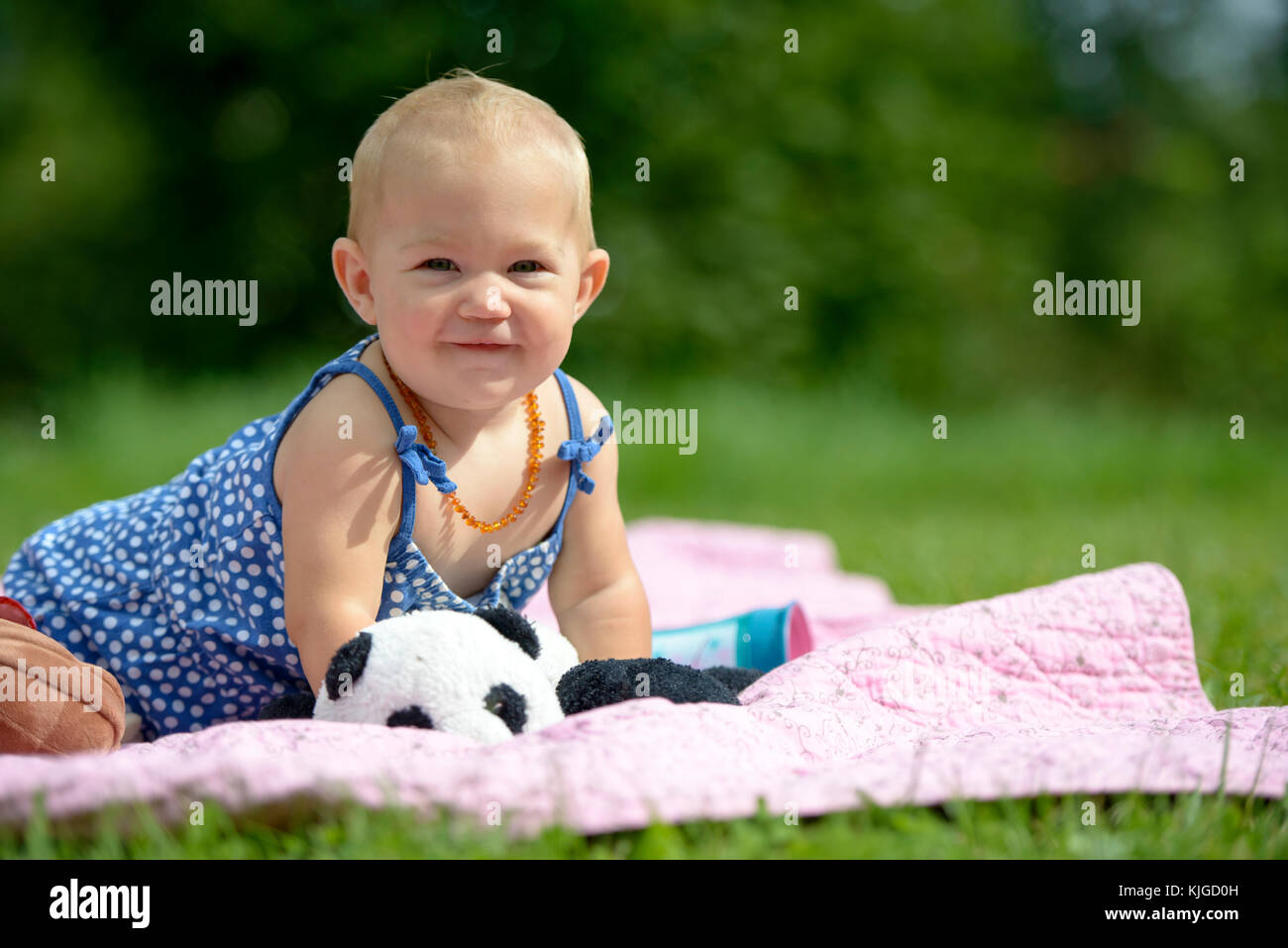 Kleines Mädchen sitzt auf circuizione Krabbeldecke im Grünen, Bayern, Deutschland Foto Stock