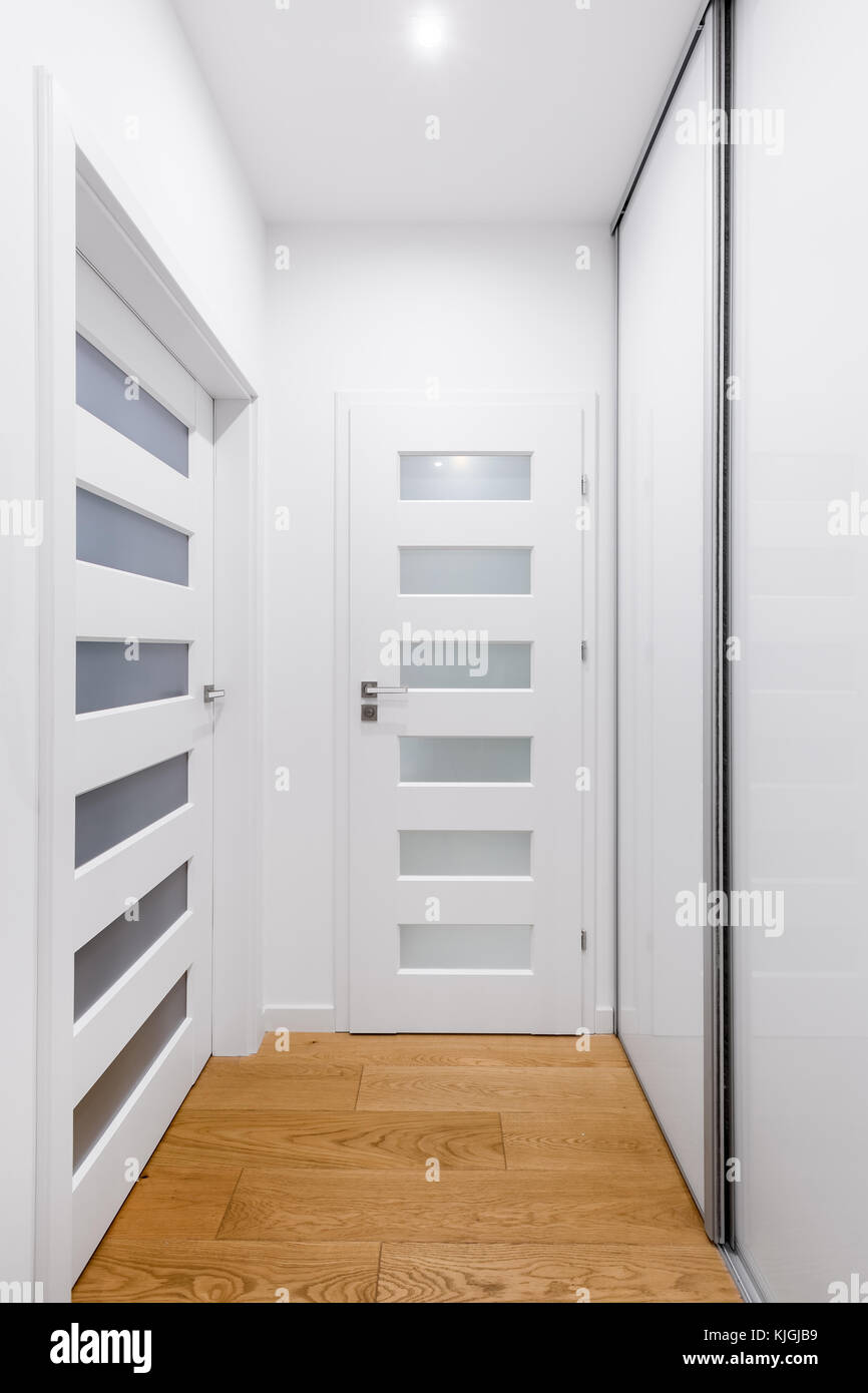 Corridoio con porte bianche, pavimento in legno e grande armadio Foto stock  - Alamy