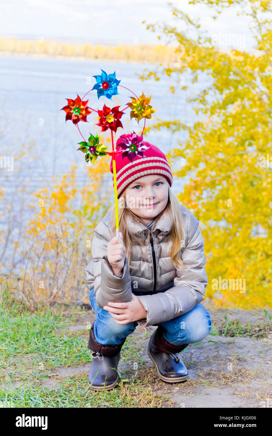 Ragazza con vento colorato giocattolo sul fiume sfondo in autunno Foto Stock