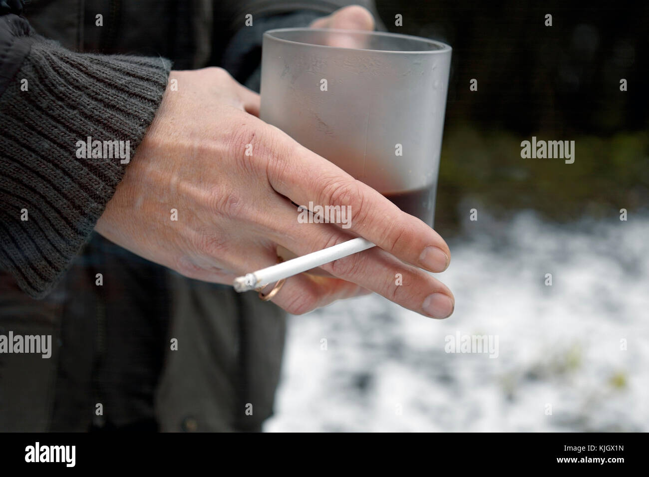 Donna che mantiene un tè o tazza da caffè e sigarette, closeup scena invernale Foto Stock
