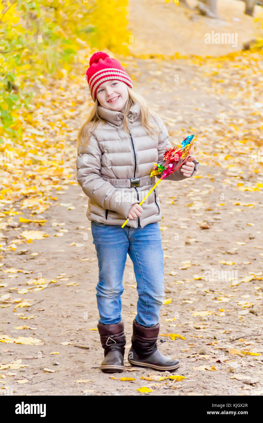 Ragazza con vento giocattolo colorati in autunno Foto Stock