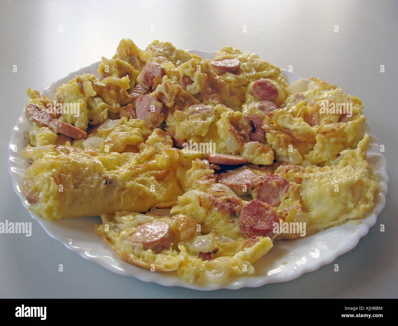 Omelette o uova strapazzate con la salsiccia tagliata a fette in un piatto da vicino Foto Stock