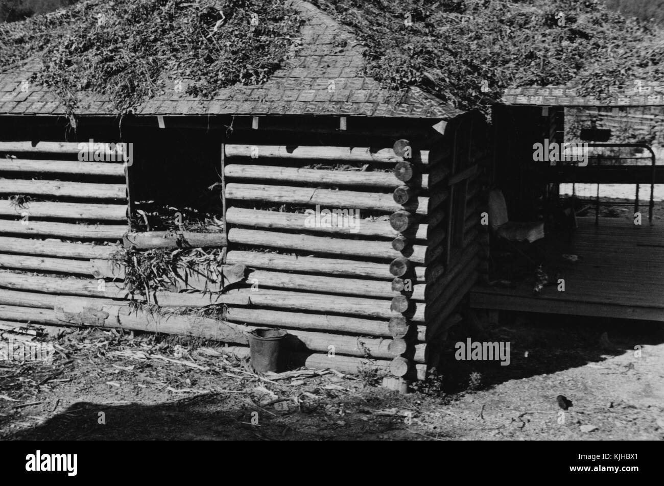 Fotografia in bianco e nero di una casa con tetto in lastre di licenza costruito dal client di riabilitazione durante la grande depressione, Arkansas, 1935. Dalla Biblioteca Pubblica di New York. Foto Stock