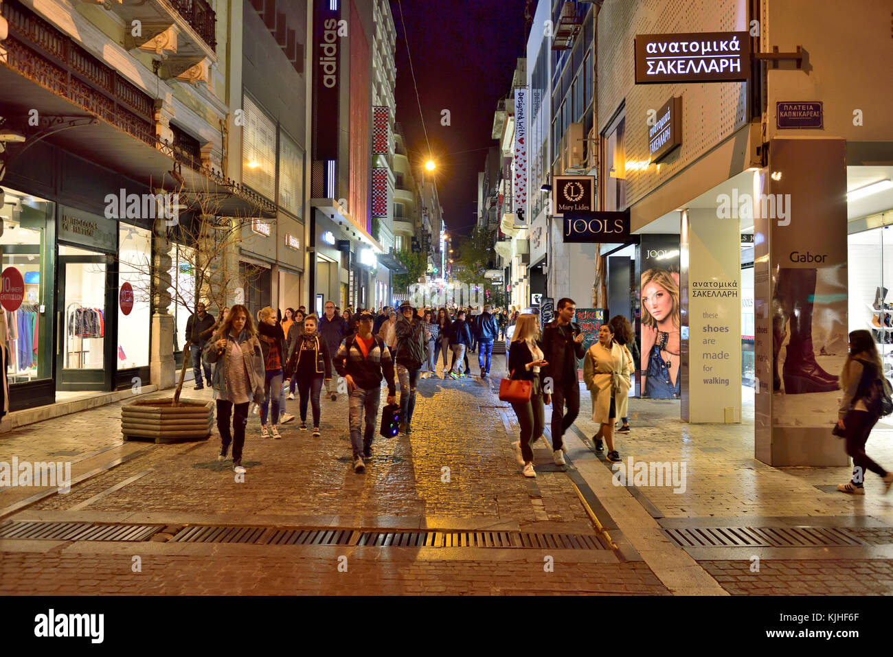 Di notte la vita di strada come persone a piedi lungo Ermou Street (uno dei negozi più famosi e socializzare strade) nel centro di Atene, Grecia Foto Stock