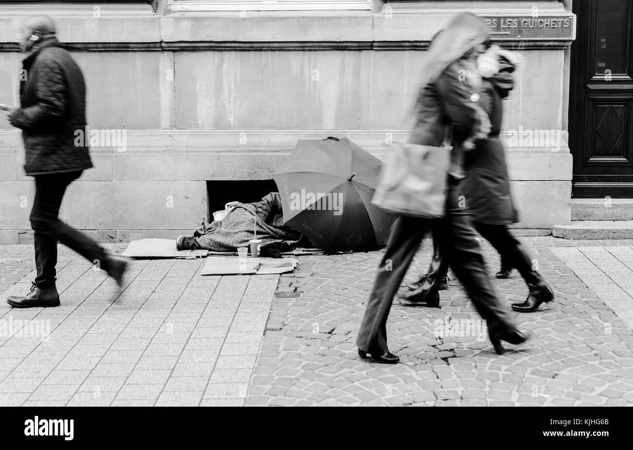 I senzatetto uomo dorme sotto l ombrello. persone stanno passando per i senzatetto uomo. versione in bianco e nero. città di Lussemburgo Foto Stock