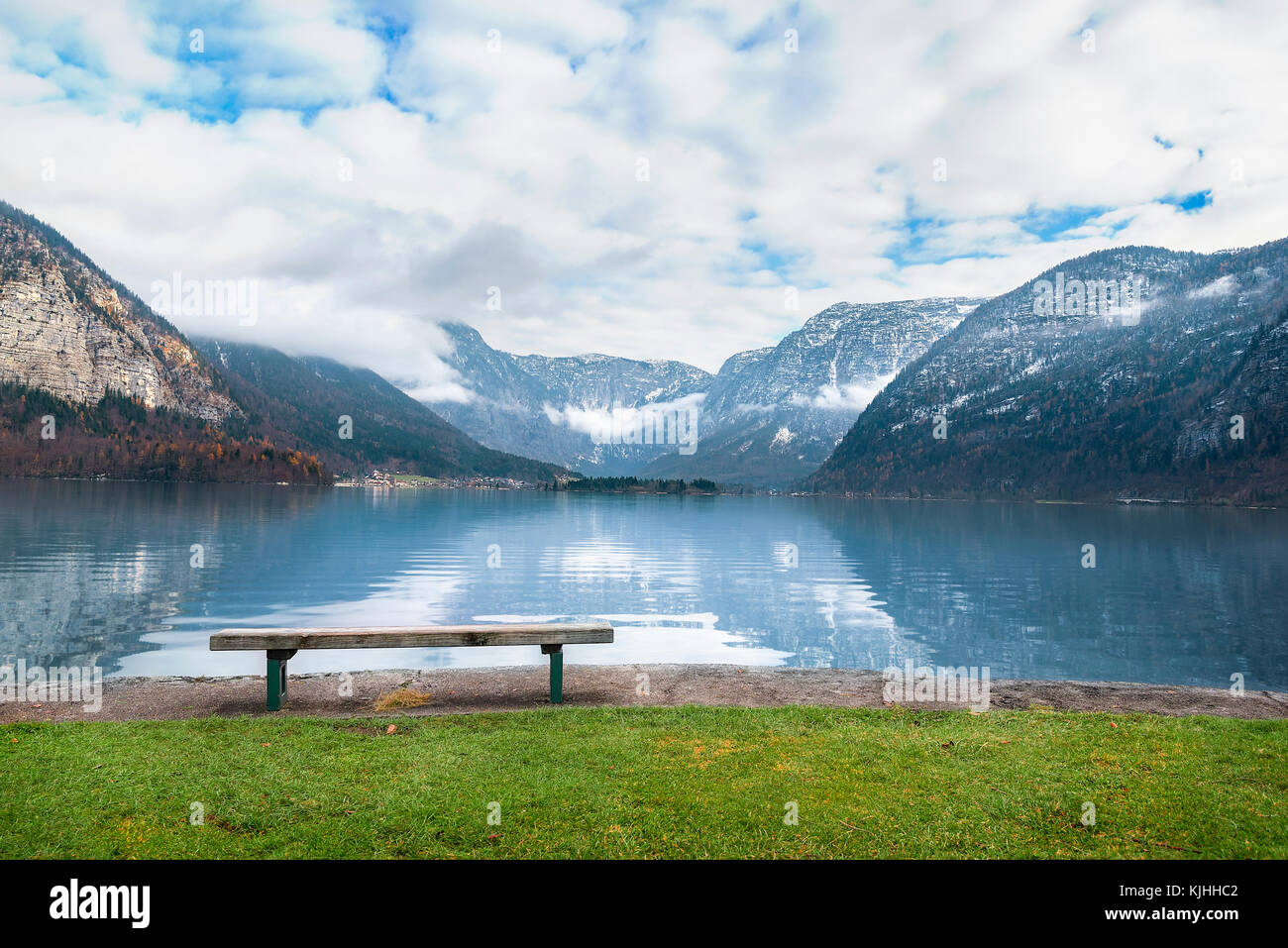 Locazioni vacanze Tema immagine con le montagne del Dachstein si riflette nel lago hallstatter acqua e una panca in legno posto sulla sua riva, in hallstat Foto Stock