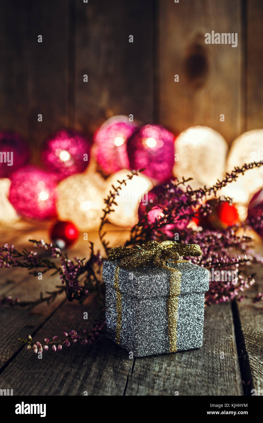 Sfondo di natale con un argento Confezione regalo e rosa essiccato heather sulla tavola di legno. luci soffuse in background. Questo può essere utilizzato come il Natale o ne Foto Stock