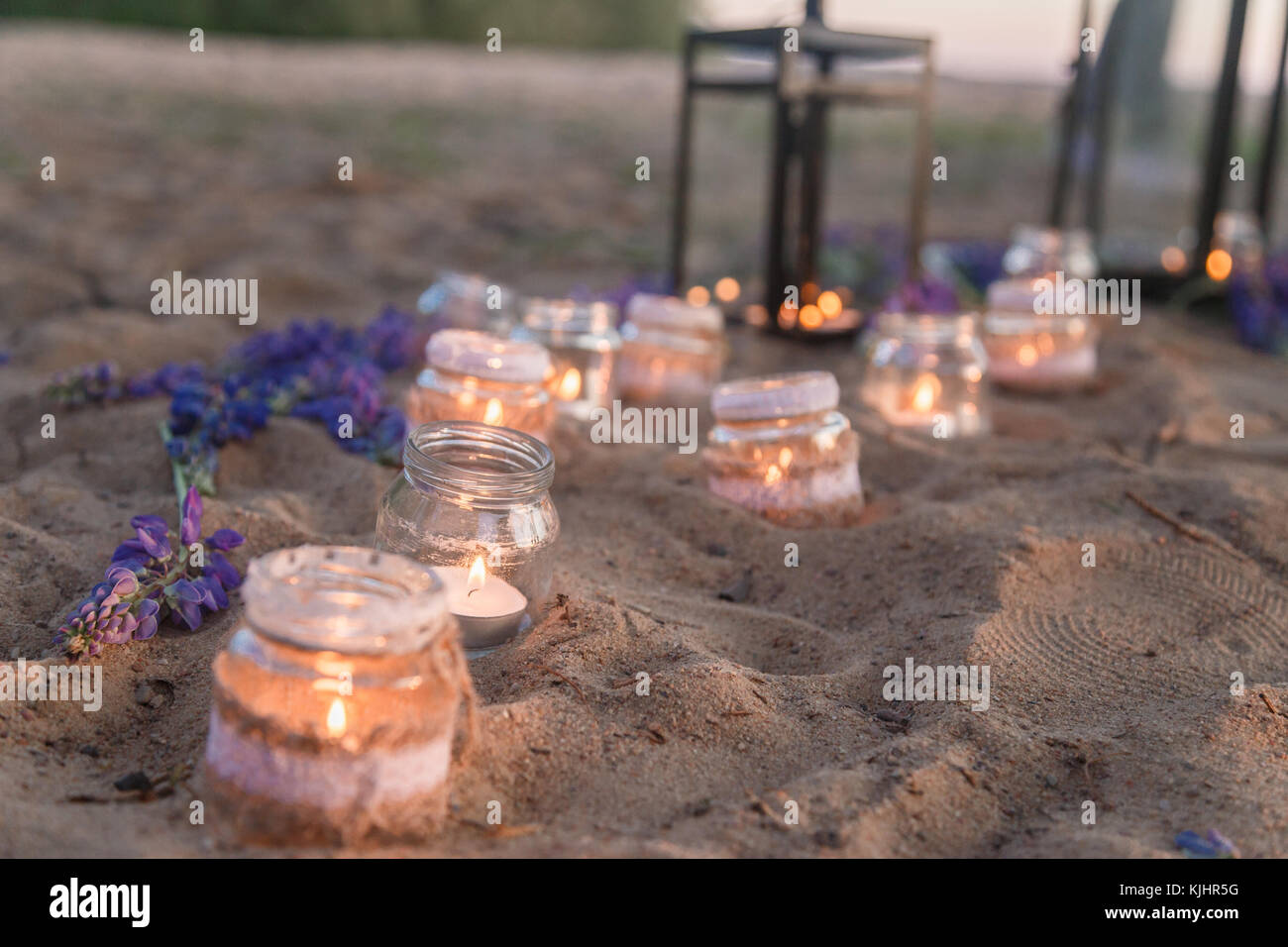 Splendidamente decorate luogo romantico per una data con vasi pieni di  candele appeso sulla struttura ad albero e in piedi su una spiaggia di  sabbia Foto stock - Alamy