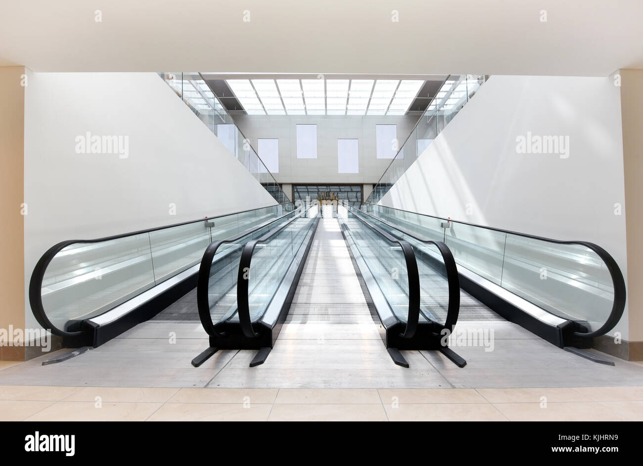 Due scale mobili vuote, uno ascendente e uno discendente, fianco a fianco in un luminoso edificio commerciale Foto Stock