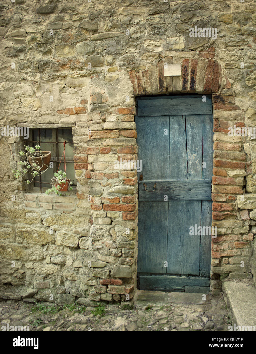 Dettaglio di una vecchia facciata con porta e una piccola finestra di casa colonica Foto Stock