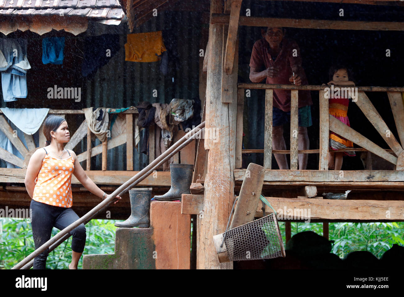 Jarai (Gia Rai) gruppo etnico. Una famiglia all'interno della loro tradizionale casa durante il monsone. Kon Tum. Il Vietnam. Foto Stock