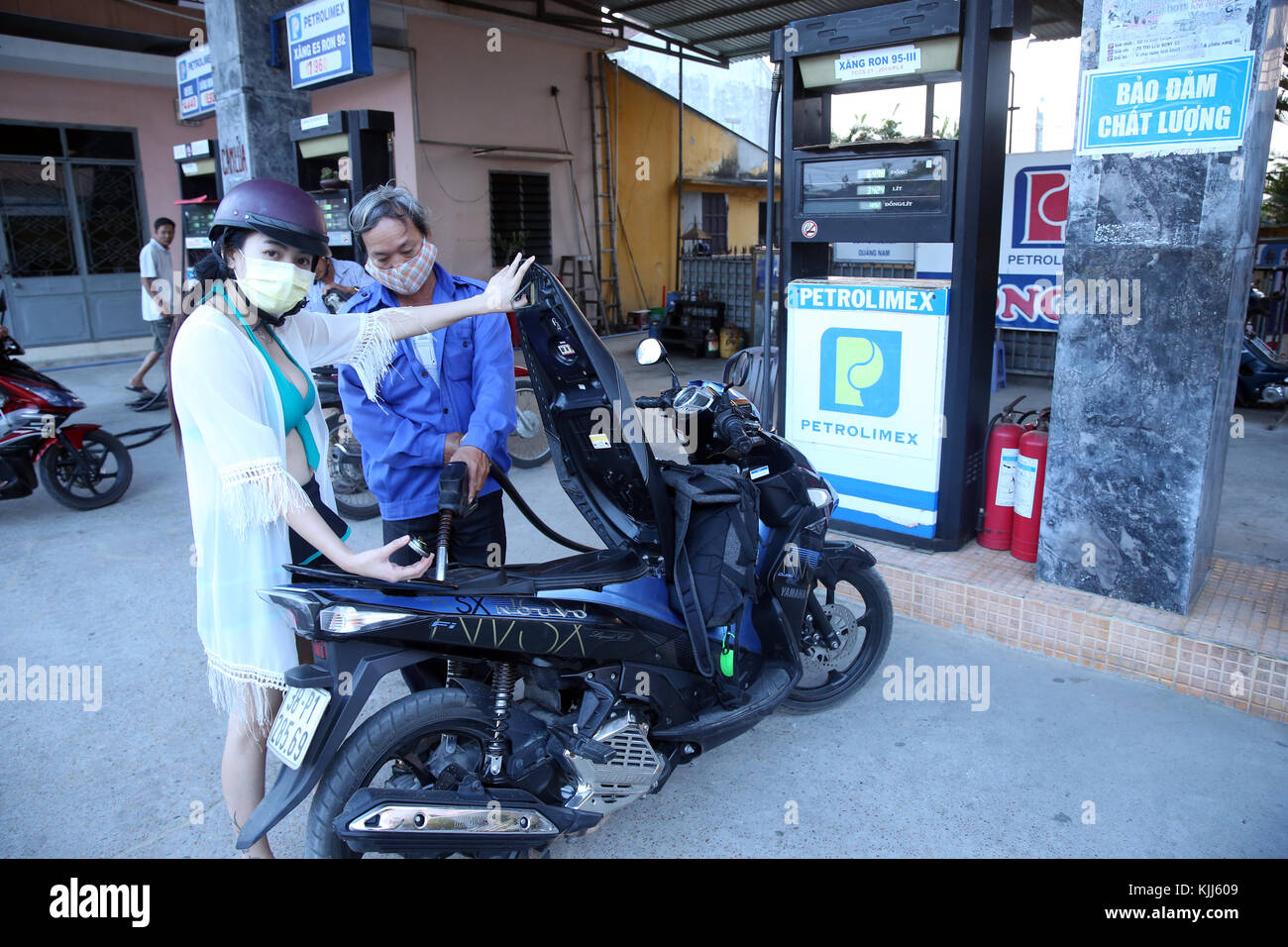 Gas station attendant riempiendo uno scooter a motore. Hoi An. Il Vietnam. Foto Stock