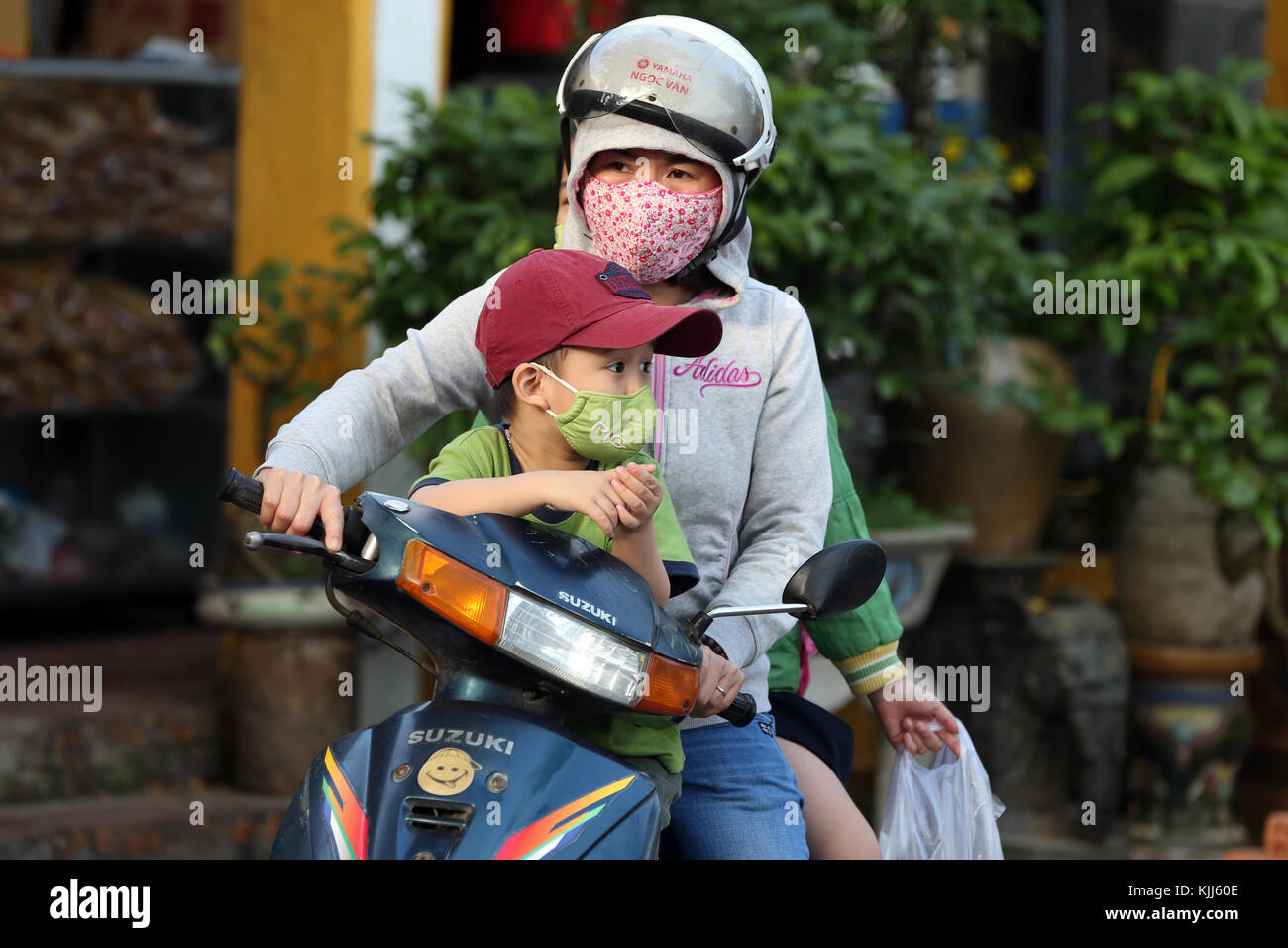 Donna con figlio guidando uno scooter. Hoi An. Il Vietnam. Foto Stock