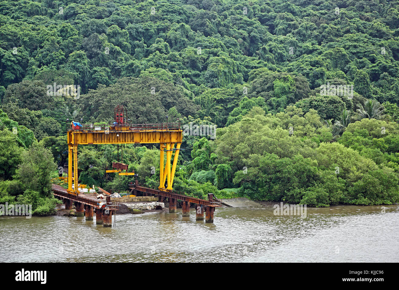 Colpo lungo della banchina di carico con il gantry crane utilizzato per il caricamento delle parti pesanti sulle barche e chiatte per la costruzione del ponte attraverso il fiume Mandovi in goa Foto Stock