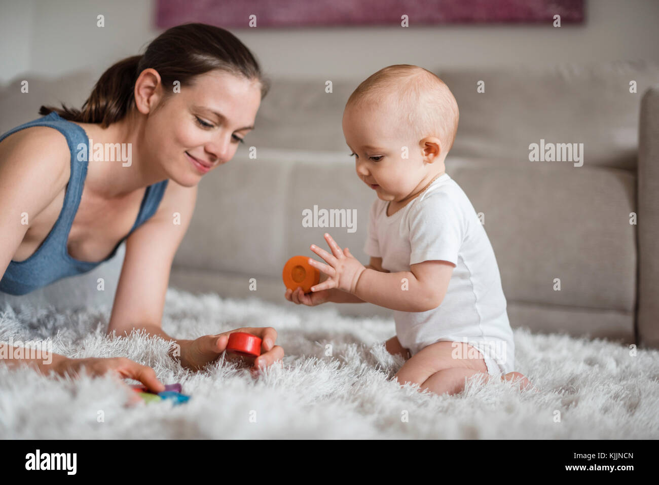 Happy Baby girl con la madre giocare su un tappeto a casa Foto Stock