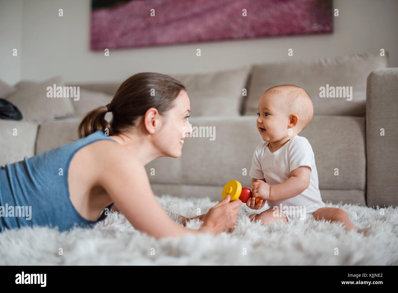 Happy Baby girl con la madre giocare su un tappeto a casa Foto Stock