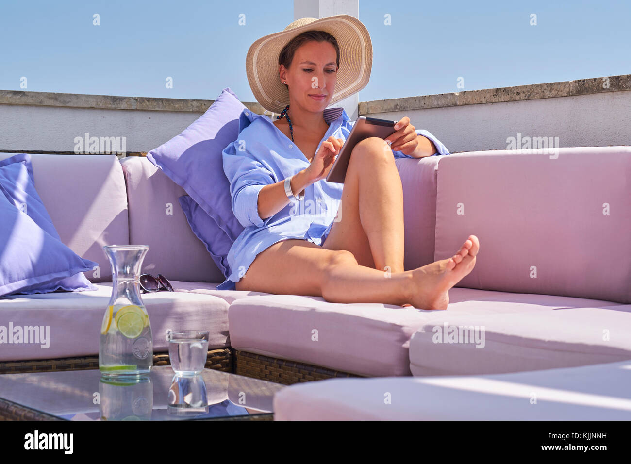Donna con la compressa rilassante su sun deck Foto Stock