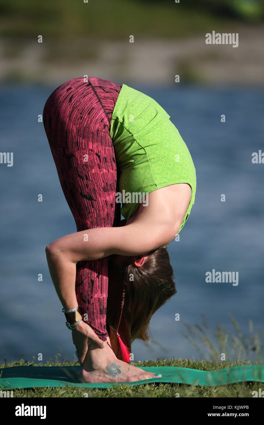 La donna a praticare lo yoga e la meditazione al di fuori. Piegamento in avanti in piedi pongono. Foto Stock