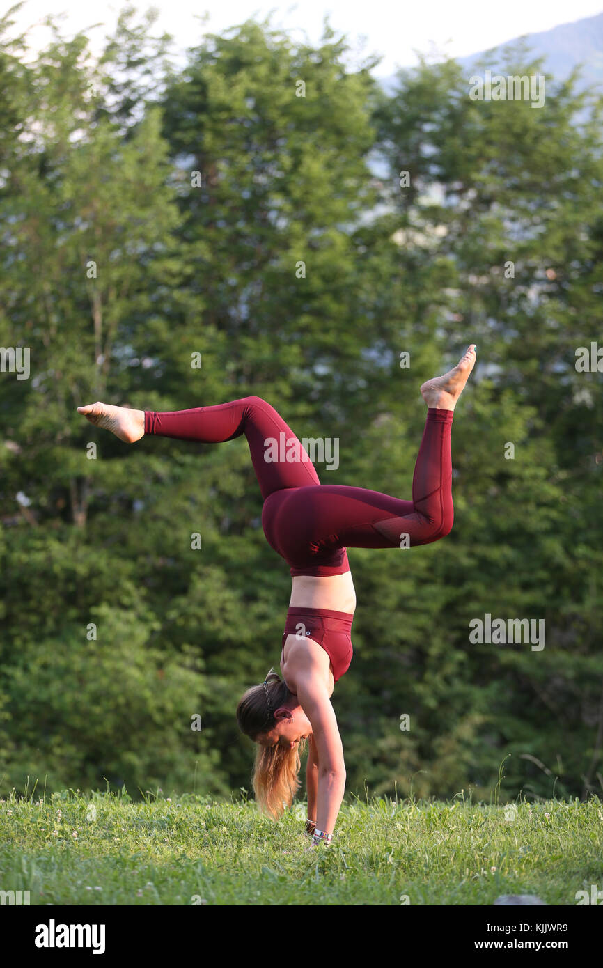 La donna a praticare lo yoga e la meditazione al di fuori. Handstand con gruppi. Saint-Gervais. La Francia. Foto Stock