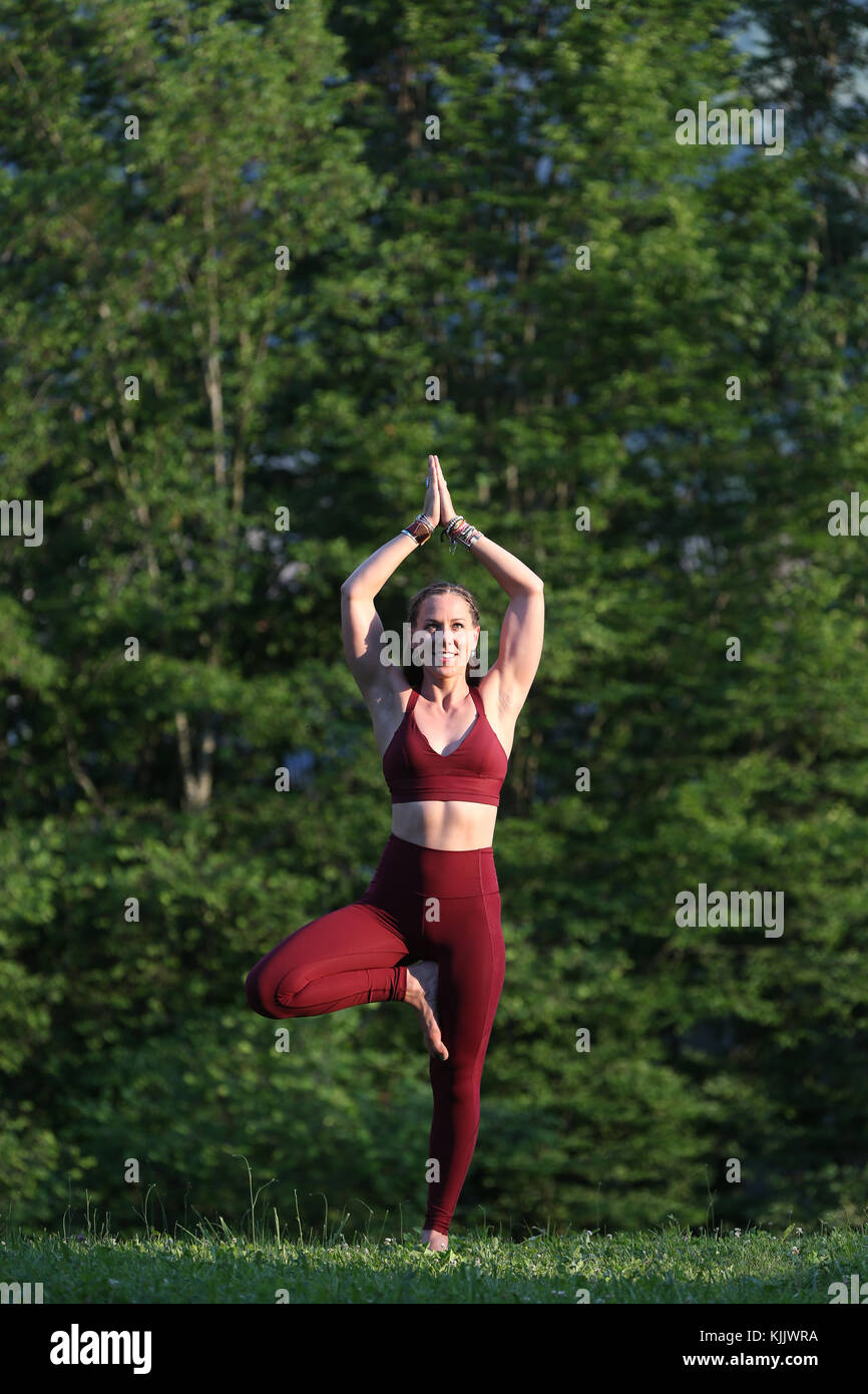 La donna a praticare lo yoga e la meditazione al di fuori. Vrksasana, la posizione dell'albero. Saint-Gervais. La Francia. Foto Stock