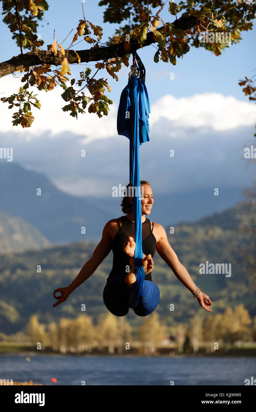 Donna facendo posa di antenna utilizzando yoga amaca all'esterno. Saint-Gervais. La Francia. Foto Stock