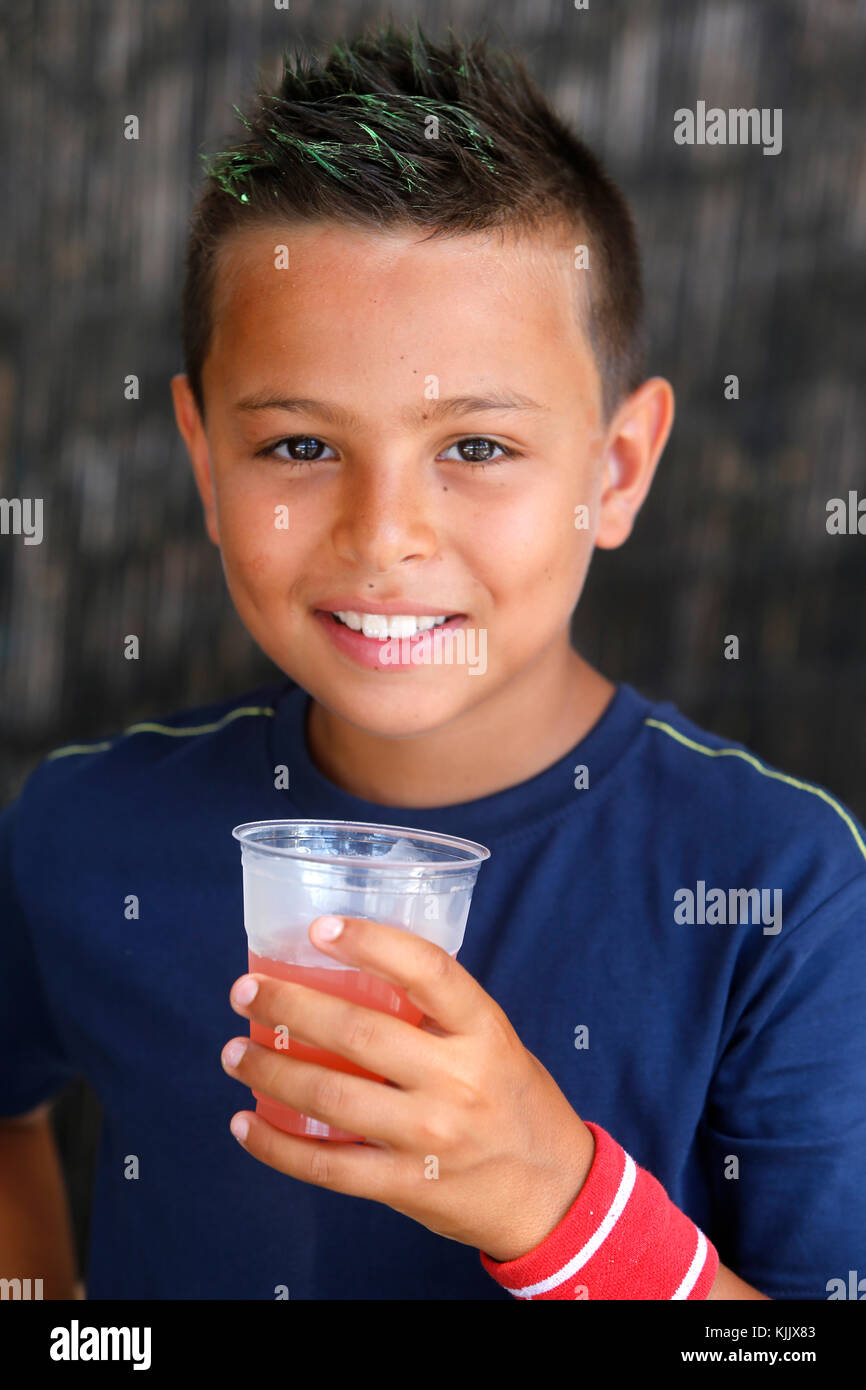 9-anno-vecchio ragazzo di bere succo di frutta. Foto Stock