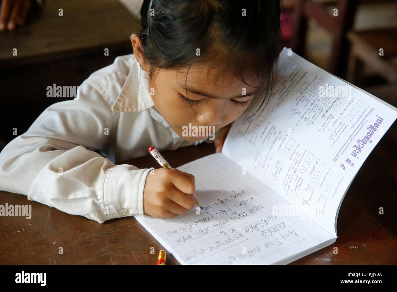 La scolaretta cambogiano iscritto in un quaderno. Battambang. Cambogia. Foto Stock