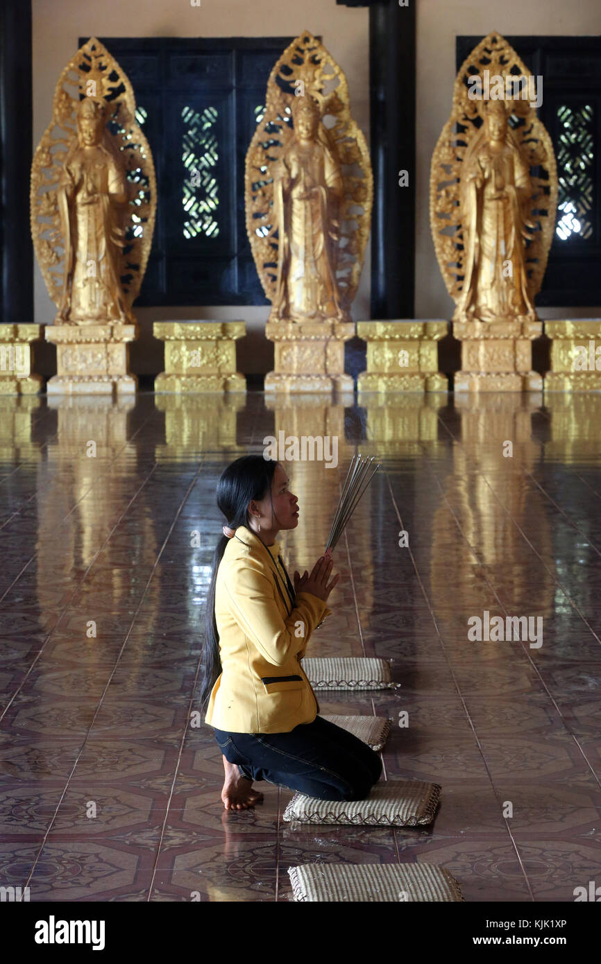 Linh una pagoda buddista. Donna in preghiera tenendo i bastoncini di incenso. Dalat. Il Vietnam. Foto Stock