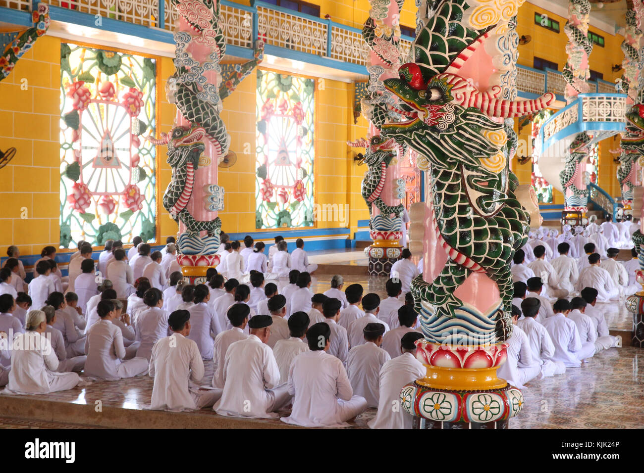 Cao Dai Santa Sede Tempio. Pregando pii uomini e donne, cerimoniale di preghiera di mezzogiorno. Thay Ninh. Il Vietnam. Foto Stock