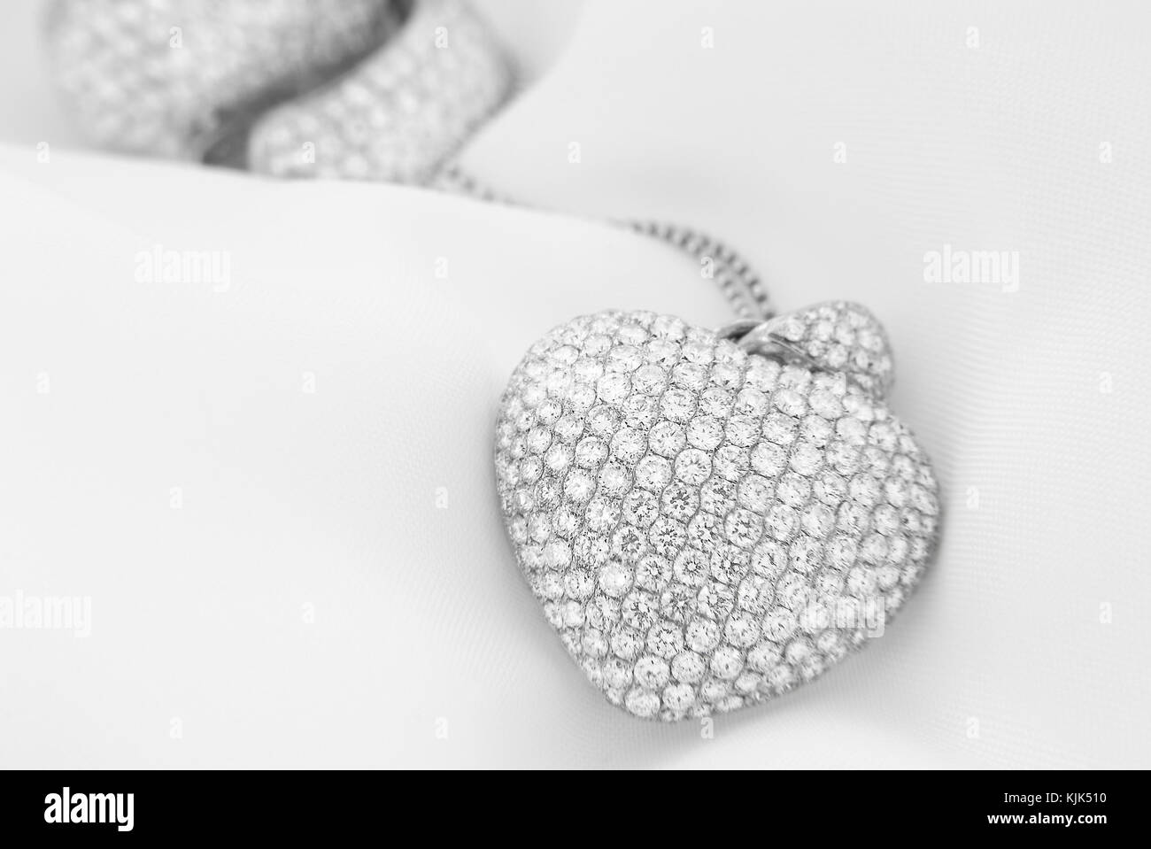 Orecchini in oro bianco a forma di cuore Collana con diamanti bianchi su morbido sfondo sfocato Foto Stock
