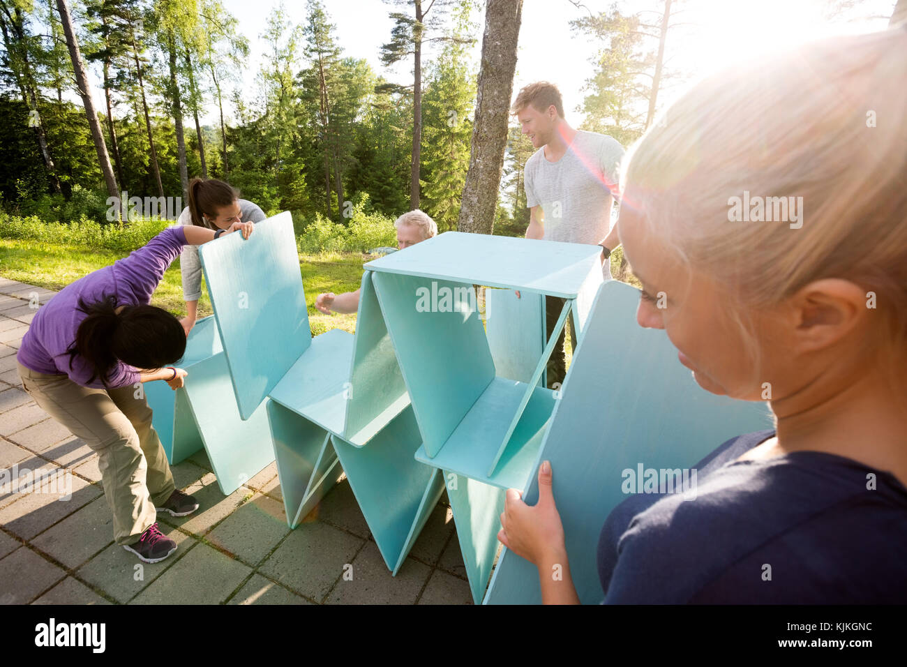 Giovane donna guardando gli amici facendo piramide delle tavole di legno sul patio in foresta Foto Stock