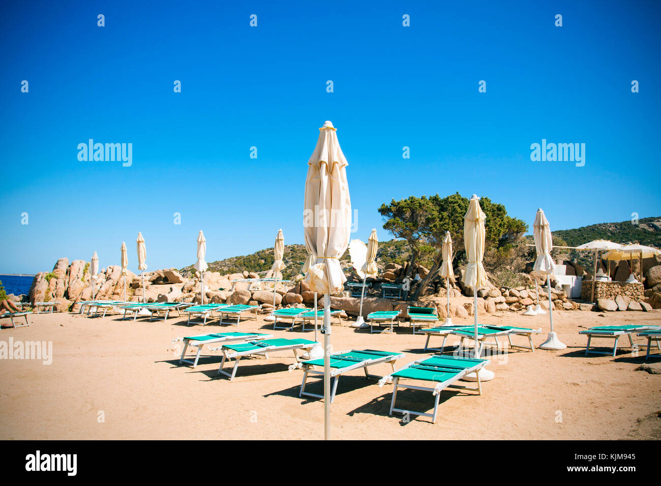 Alcuni lettini e ombrelloni in una spiaggia di Baja Sardegna, Sardegna, Italia Foto Stock