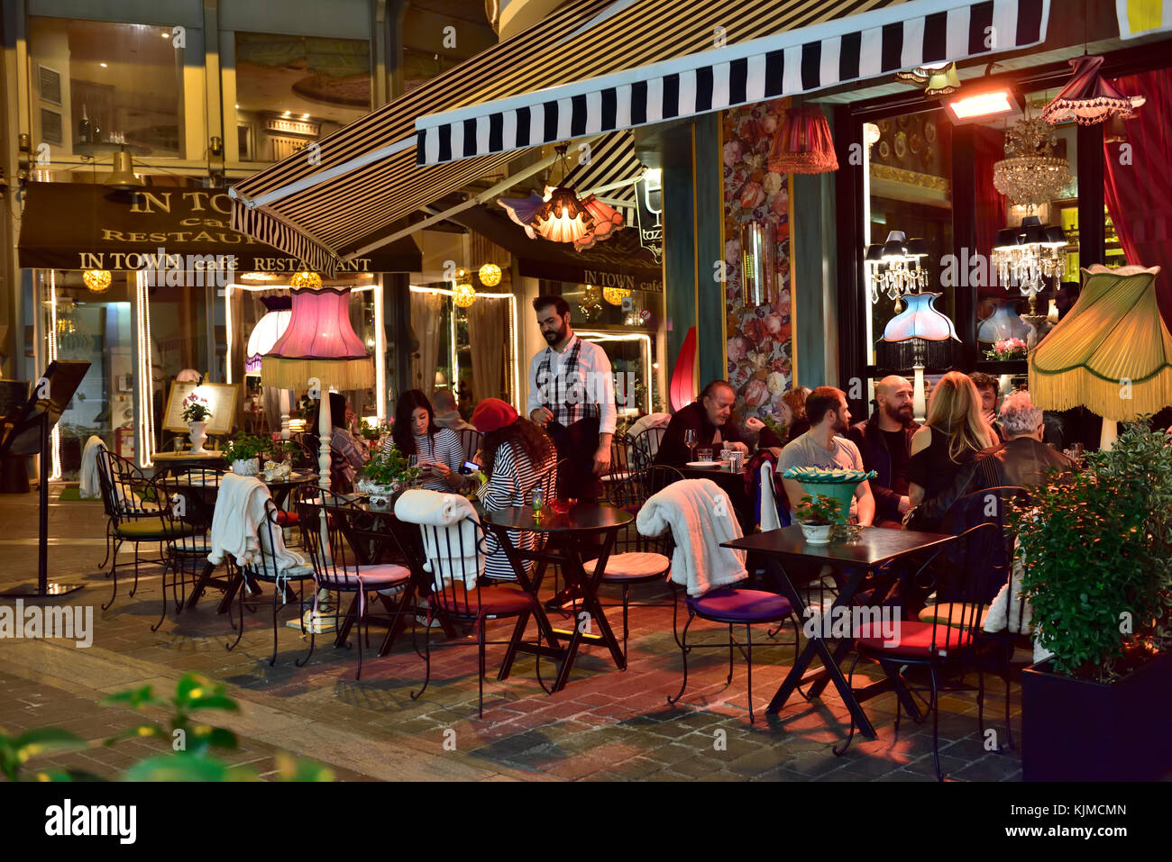 Di notte la vita di strada con le persone all'esterno pavement cafe bar nel centro di Atene, Grecia Foto Stock