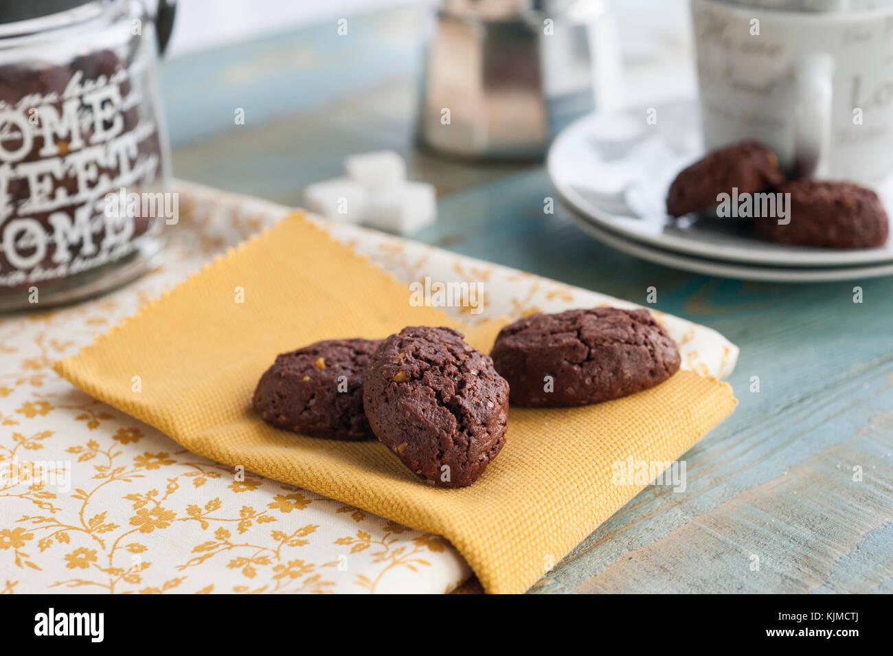 I cookie di rustico con cacao e pistacchi di Bronte sul vassoio decorato e panno assorbente e altri articoli per la cucina in background Foto Stock