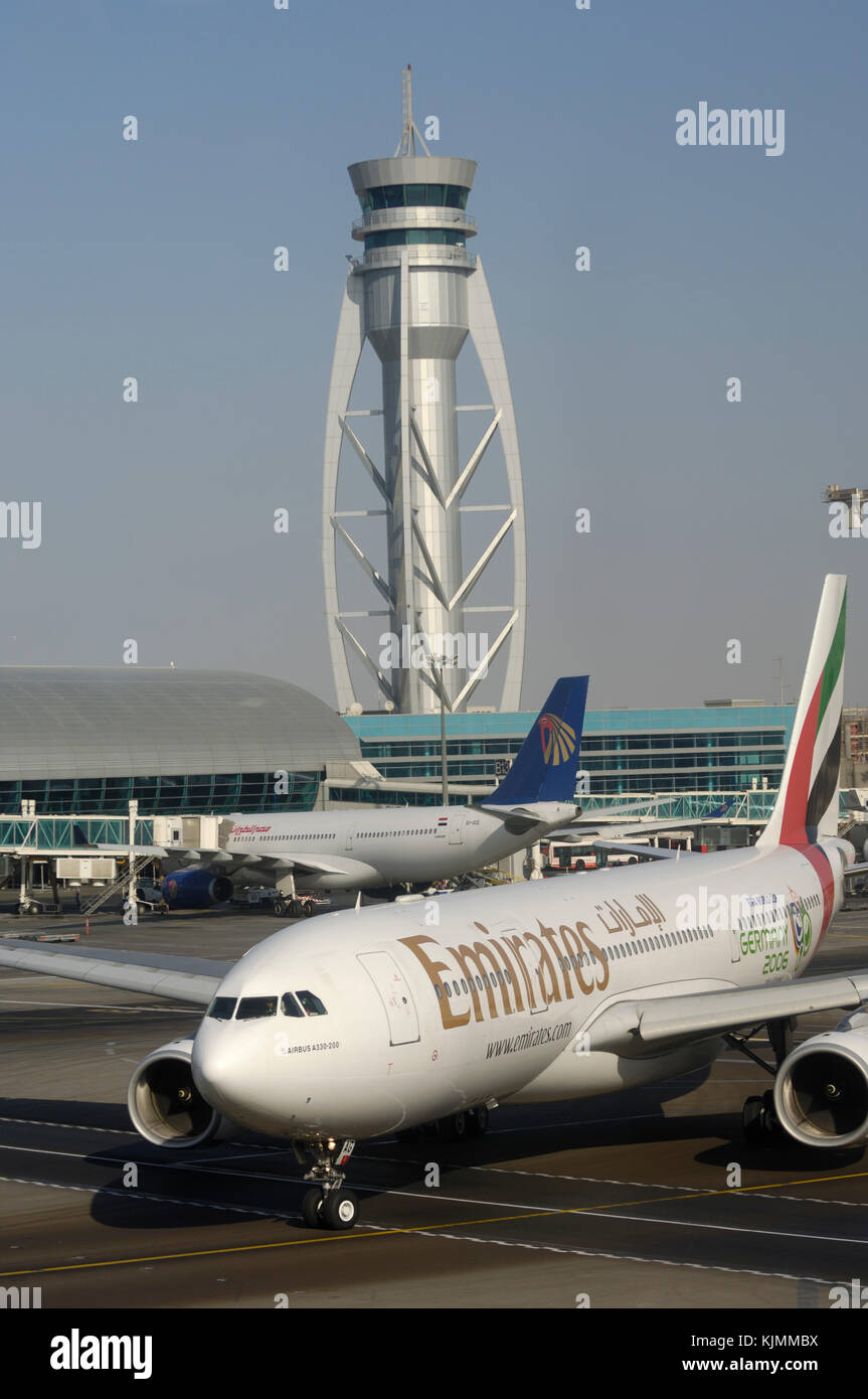 Emirates A330 rullaggio passato un Egypt Air A330-200 con controllo a torre dietro Foto Stock