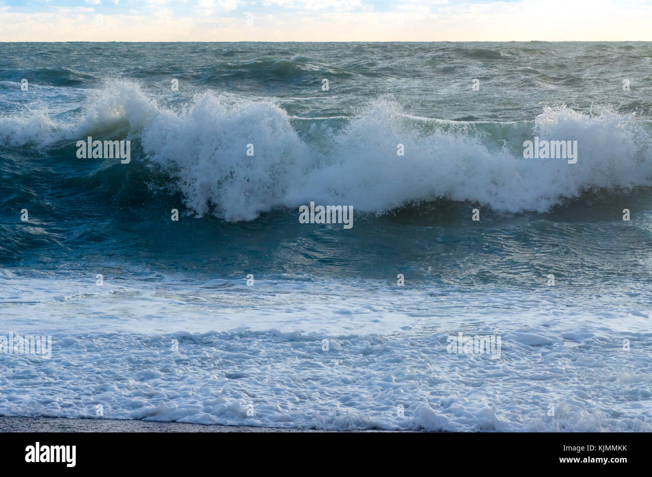 Onda di mare in tempesta di formazione di schiuma di colpire la spiaggia splendidamente Foto Stock