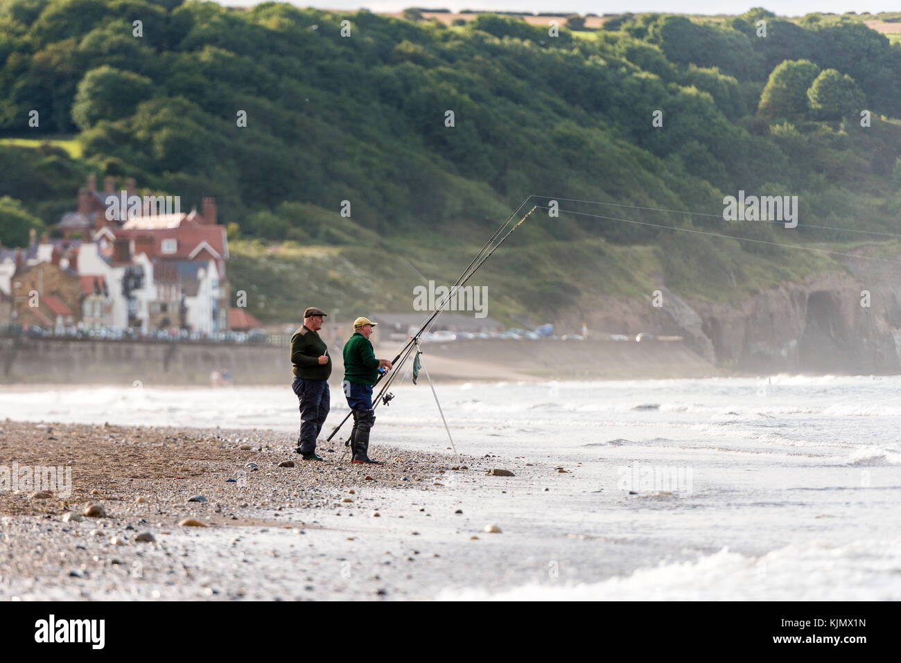 Due uomini che pescano sulla spiaggia di Sandsend, whitby, regno unito Foto Stock