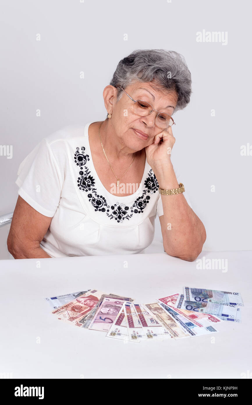 Una vecchia donna che indossa gli occhiali cercando denaro Foto Stock
