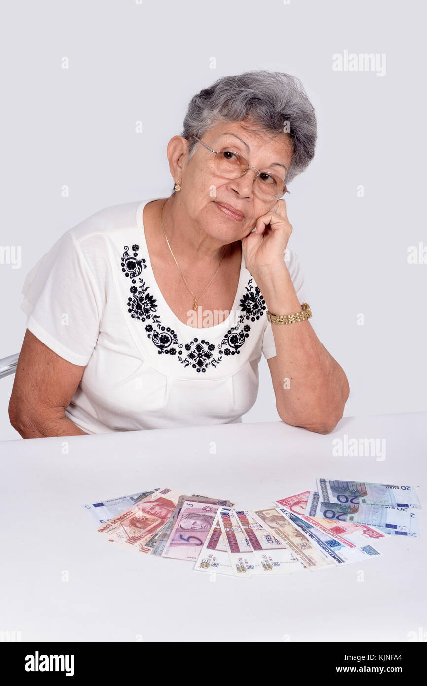 Una vecchia donna che indossa occhiali con denaro sulla scrivania Foto Stock