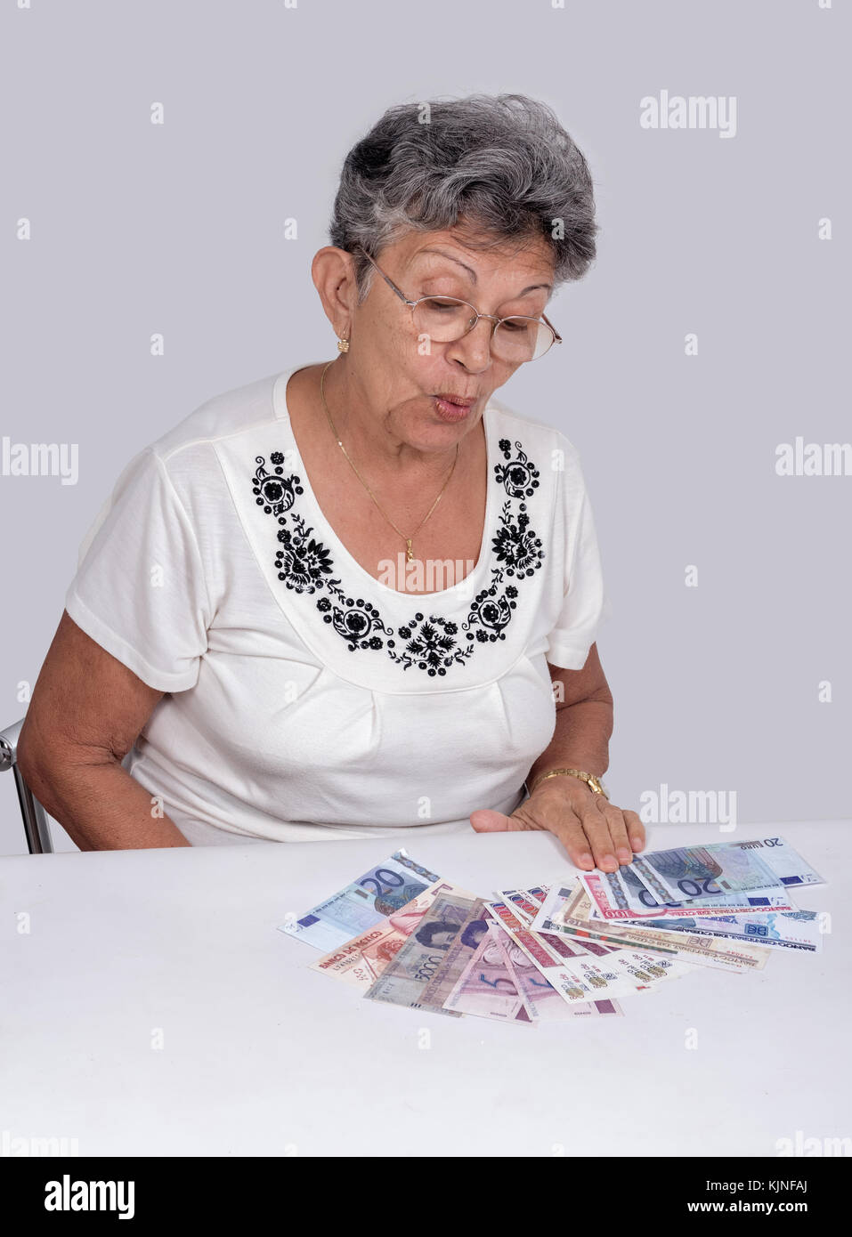 Una vecchia donna che indossa occhiali con denaro sulla scrivania Foto Stock