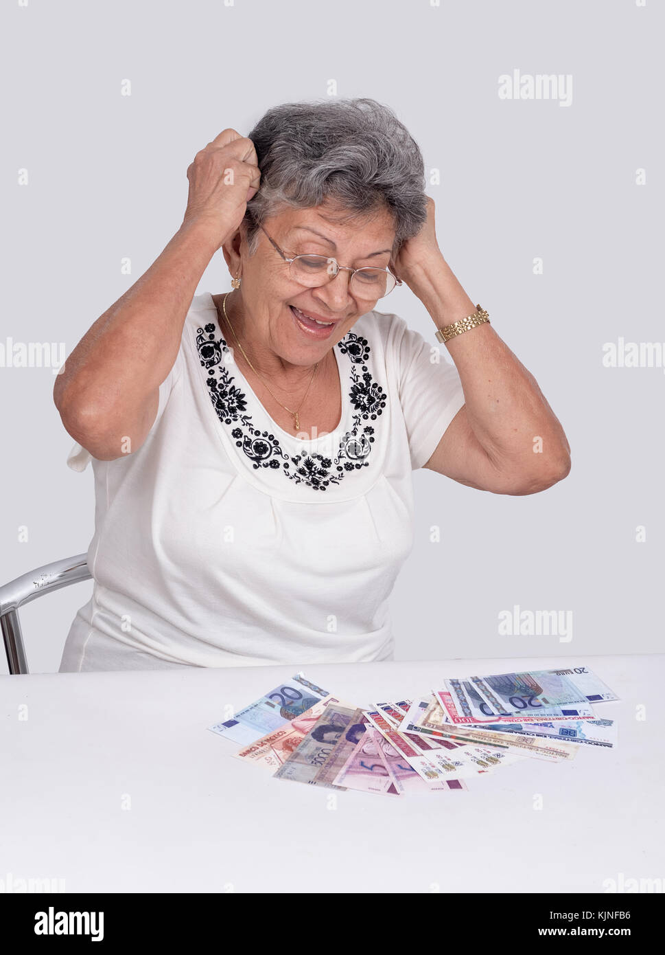 Un felice vecchia donna indossa occhiali cercando denaro Foto Stock