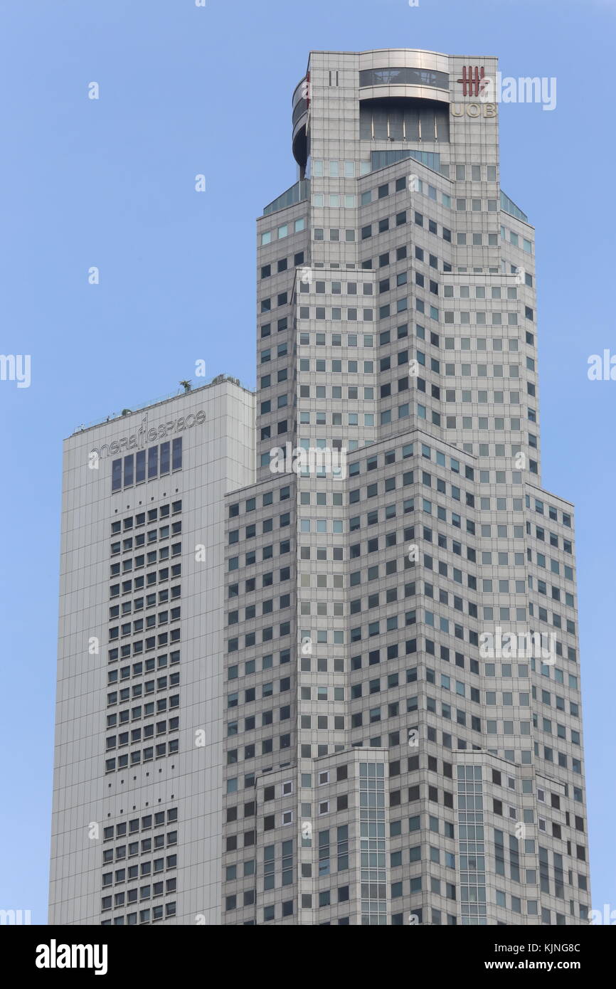 Dettaglio della parte superiore di un edificio alto e moderno in Singapore con molte finestre. Lo sfondo è blu e la parte superiore del skycraper è grigio. dolce texture. Foto Stock