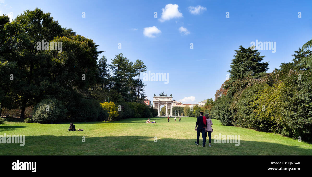 Coppia giovane a piedi all'Arco della Pace che attraversa un parco, Milano, Italia Foto Stock