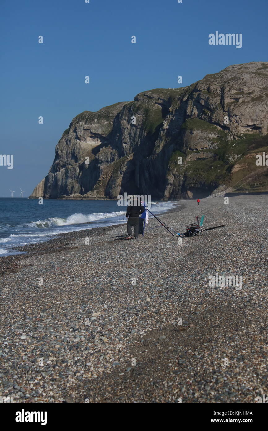 Gli uomini la pesca sulla spiaggia di ciottoli a Llandudno fronte mare Foto Stock