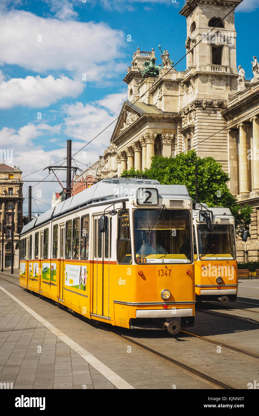 Tram gialli di fronte al Museo di Etnografia a Budapest (Ungheria). Giugno 2017. Formato verticale. Foto Stock