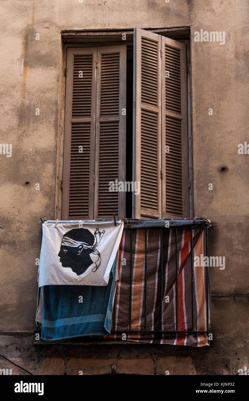 Ajaccio: Bandiera della Corsica, una testa di moro in nero che indossa una bandana sopra i suoi occhi, adottata nel 1755, su un balcone con biancheria stesa ad asciugare Foto Stock